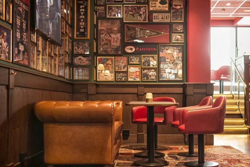 Sitteområde på O'Learys Drammen med brun skinnsofa, røde stoler og vegger dekorert med sportsplakater.