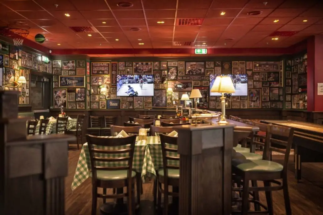 Spiseområde på O'Learys Drammen med rutete duker, sportsdekor på veggene og skjermer som viser sport.