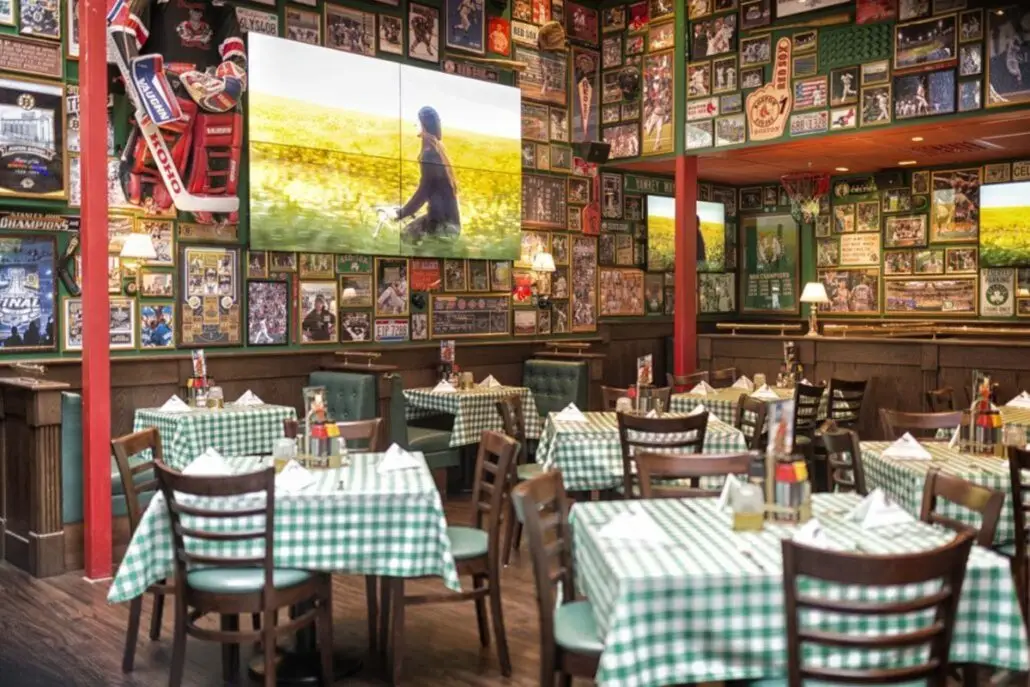 Spiseområde på O'Learys Drammen med grønne rutete duker, sportsdekor på veggene og TV-skjermer som viser sport.