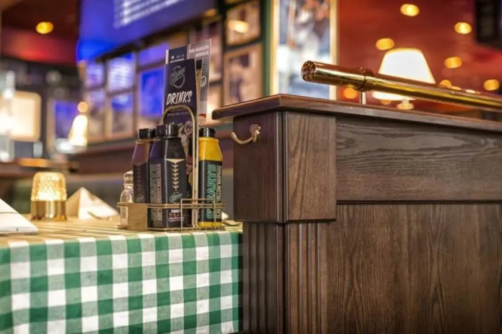 Bord på O'Learys Drammen med grønnrutet duk, menyer og flasker med sauser i holder.